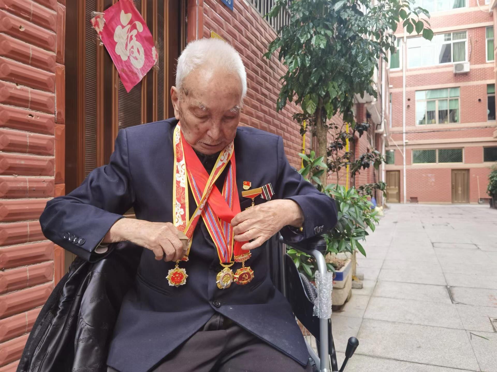 陈友忠老兵向我们展示徽章 拍摄：骆艳芳.jpg